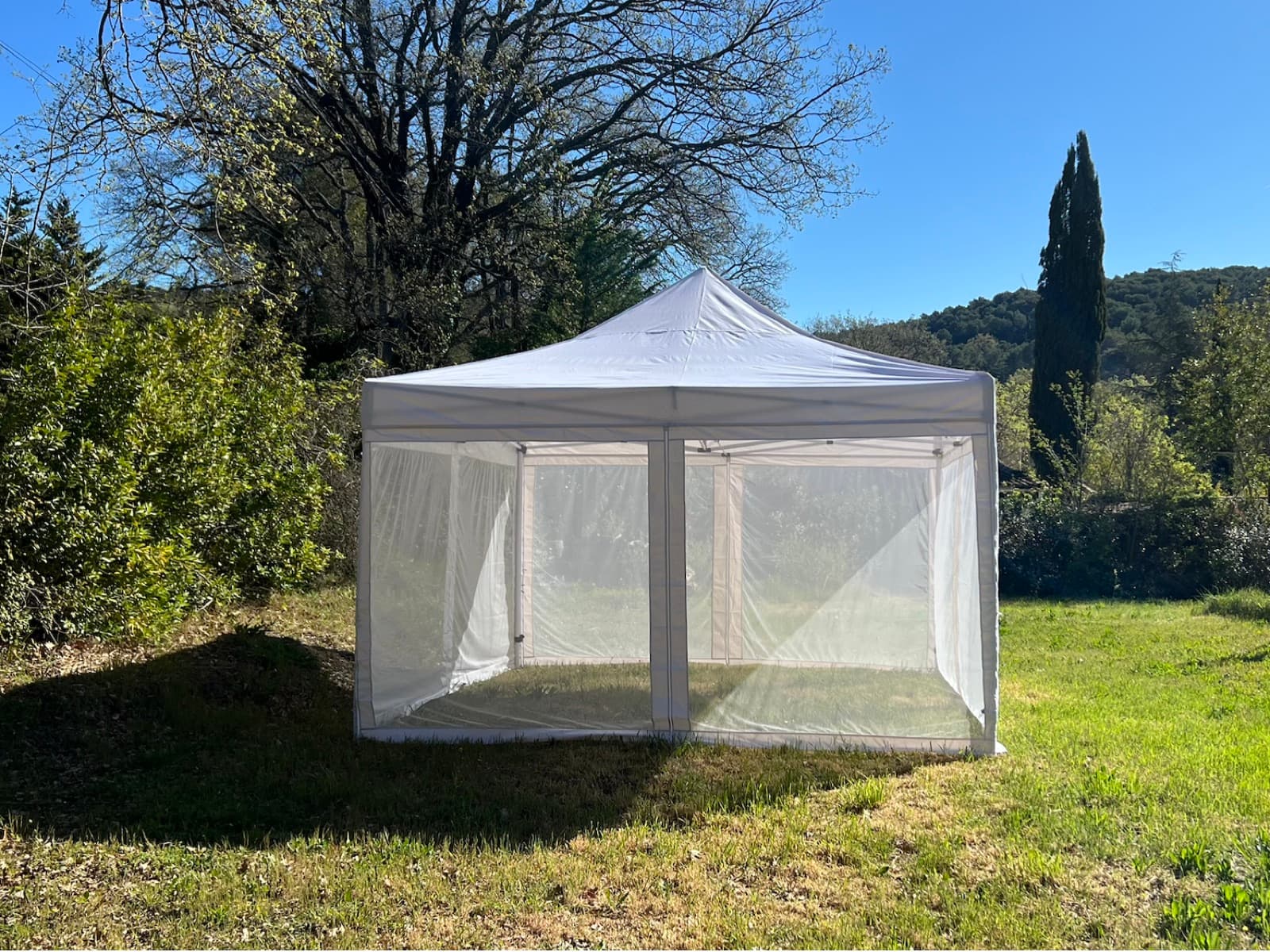 The Mosticare Terrazza gazebo with zip-up mesh walls standing in a Mediterranean garden.