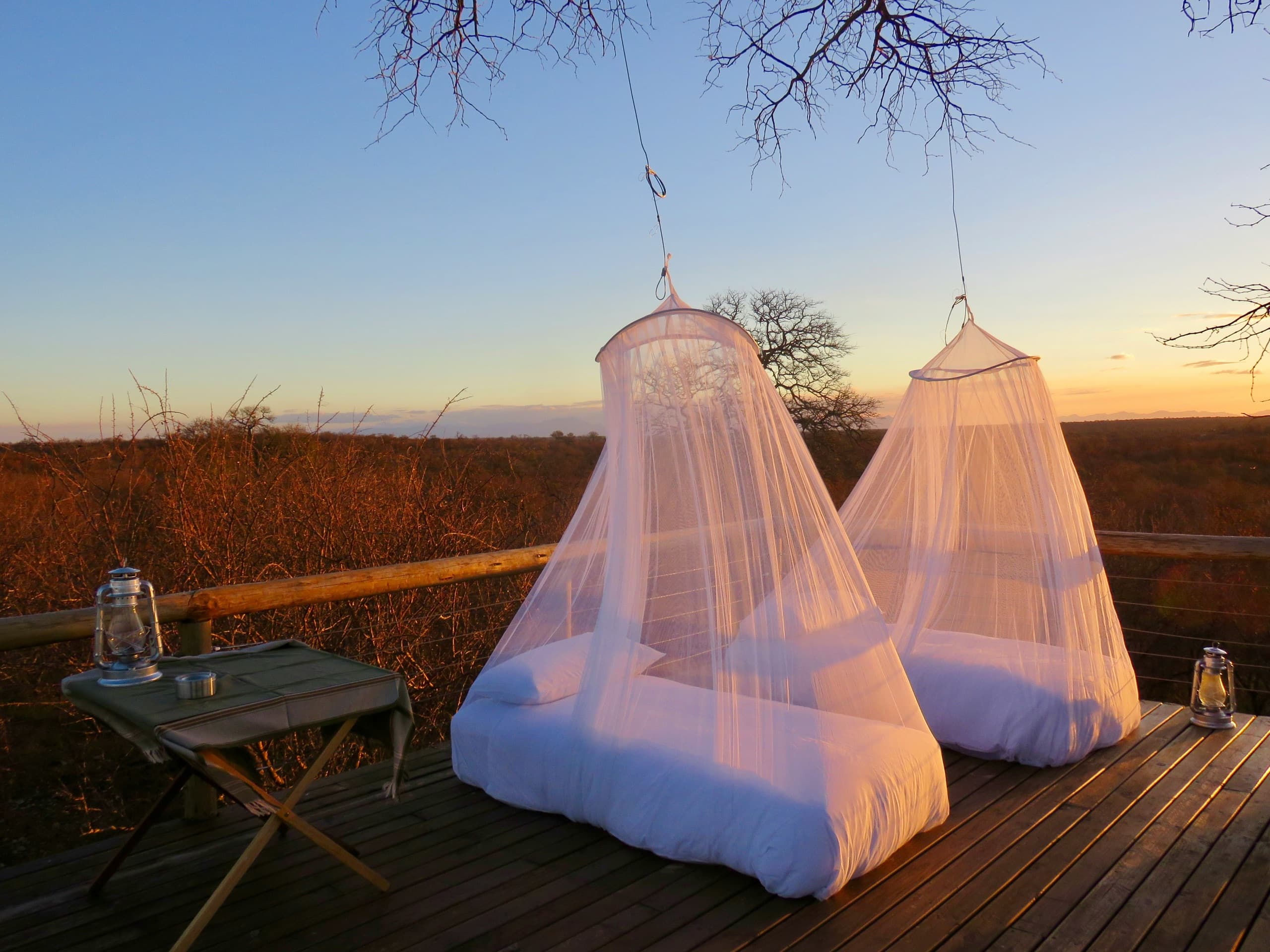 Two Mosticare Rondo canopies over beds on a deck at dusk